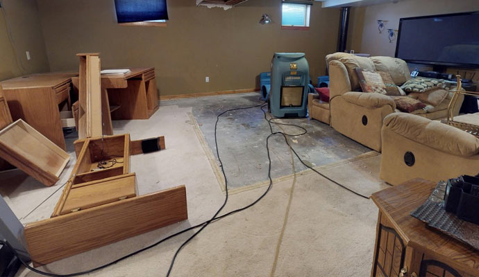 A dehumidifier and air mover in a basement with removed carpet
