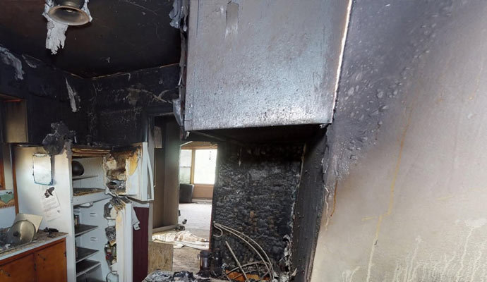 A soot covered kitchen with smoke and fire damage