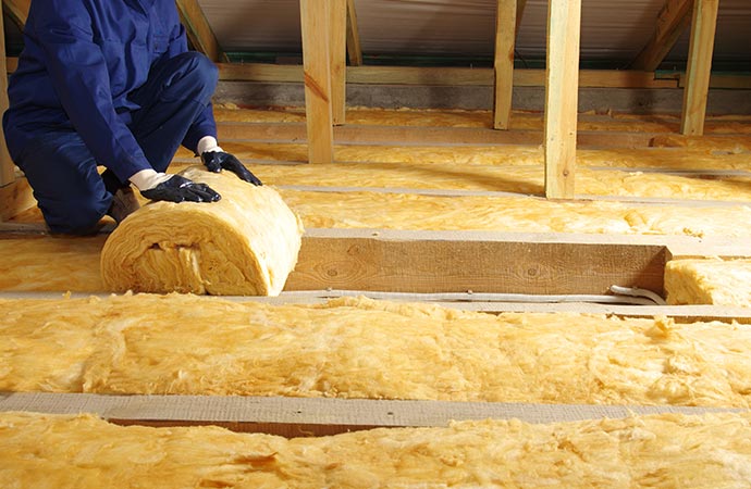 A worker installing fiberglass insulation for smoke damage repair