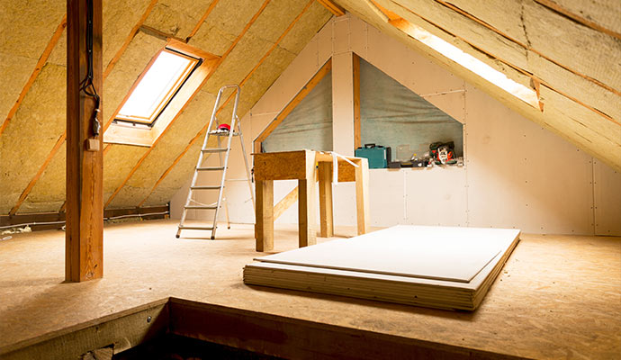 An attic with fiberglass insulation skylights and drywall
