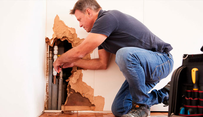 worker repairing damaged burst pipe