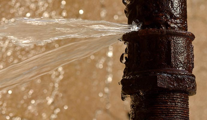 Close-up of a broken rusty metal pipe leaking water