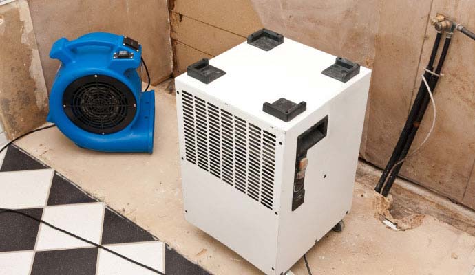 Industrial dehumidifier and air mover drying a room during water removal
