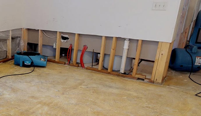 Flood cut walls with exposed studs and blue air movers
