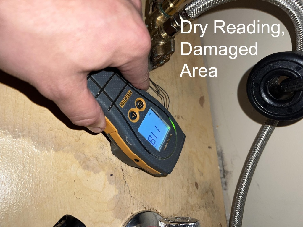 A dry reading confirmed by a moisture meter in a previously damaged kitchen cabinet area, ensuring successful water mitigation and structural drying services to prevent mold growth.