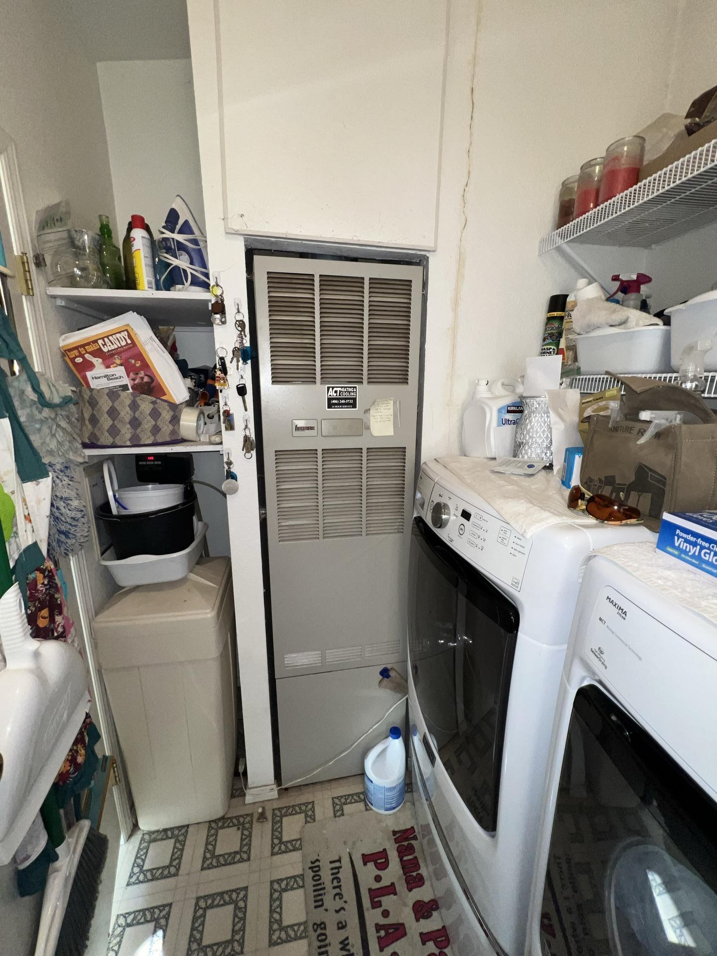 Close-up of a laundry room showing a boiler closet next to a washing machine, with visible discoloration or growth on the drywall indicating water damage.