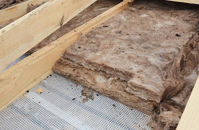Pink insulation batts between wooden floor joists