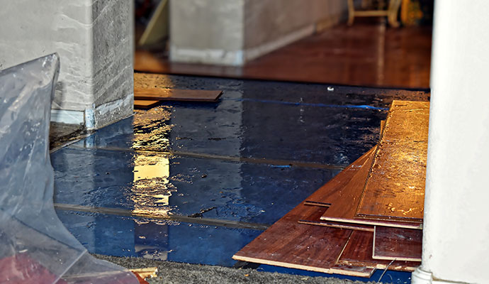 Removed hardwood planks and a blue moisture barrier on the floor