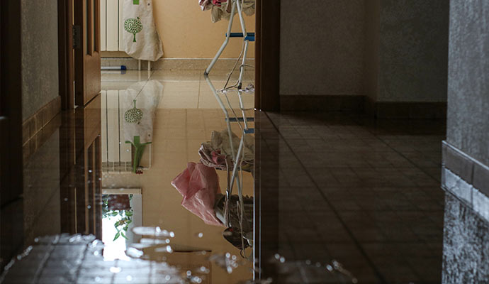 Standing water on a floor reflecting a laundry rack