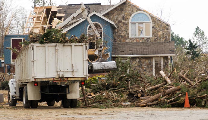 Cleanup truck clearing storm debris from disaster-damaged property
