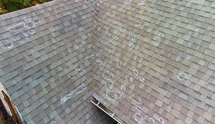 Roof shingles showing several hail-damage areas highlighted with white circles