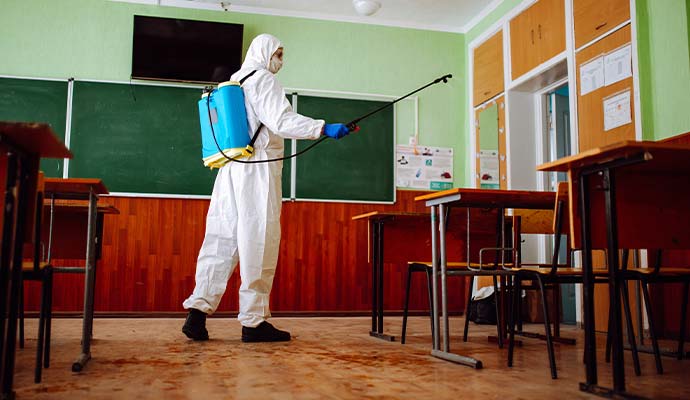 Technician disinfecting school classroom