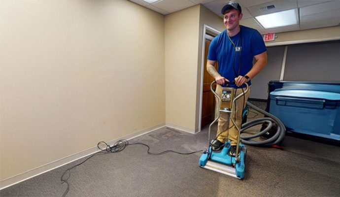 Professional extracting water from carpet using equipment