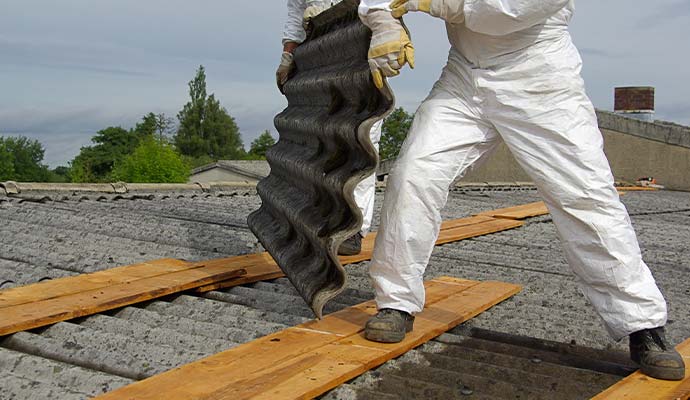Worker removing asbestos from roof sheets