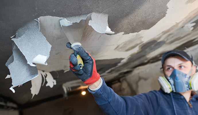 Worker scraping soot from ceiling